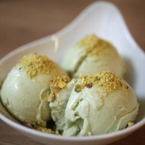 Boules de glace pistache artisanale servies dans une coupelle avec éclats de pistache